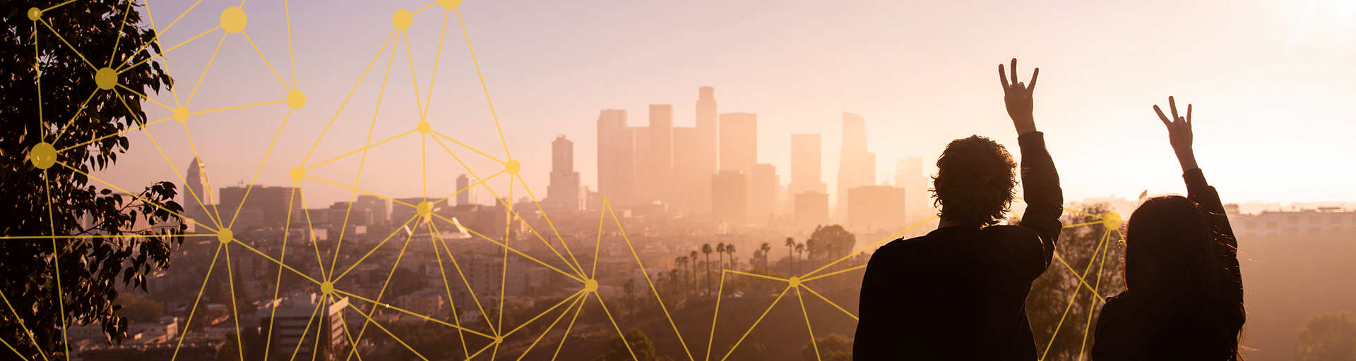 silhouettes of people holding the pitchfork hand symbol in front of city skyline at sunset