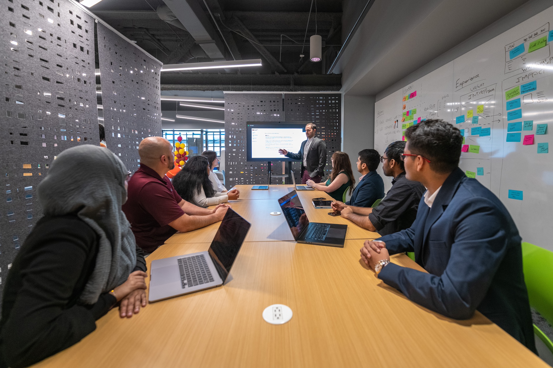 AI team sitting and listening to speaker presenting at the head of the table