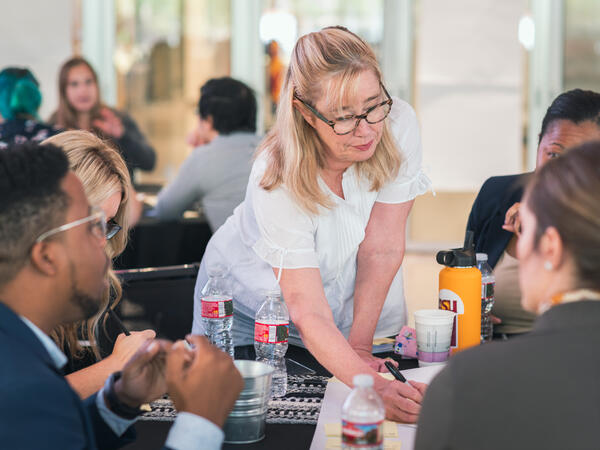 ASU employee writing on sticky notes on table with colleagues