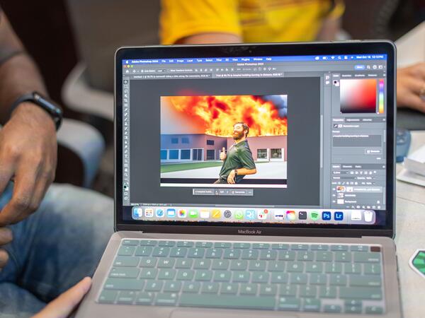 laptop screen with image of building on fire being edited in Adobe Photoshop