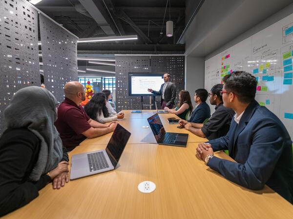 AI team sitting and listening to speaker presenting at the head of the table