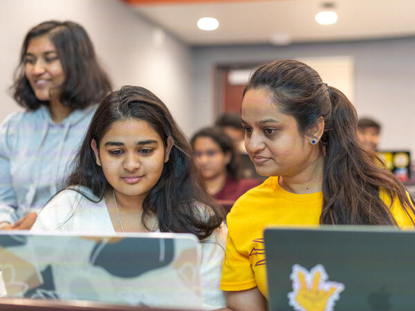 two students working on a laptop