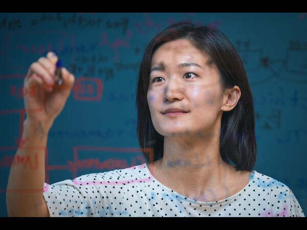Person writing on clear board in front of them